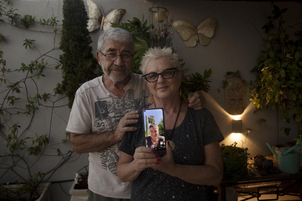 Moshe and Suzi Malinovitz pose for a portrait at their apartment in Rehovot, Israel, with their daughter, Ronit Malinovitz, seen on screen from Phoenix, Ariz., Tuesday, July 27, 2021. While Ronit's parents were able to visit her in the Phoenix suburbs in the spring, she called off a trip to Israel this summer to see them and other relatives because of what she said was an overwhelming amount of paperwork involved in applying for Israeli passports for her two teenage daughters. (AP Photo/Maya Alleruzzo)
