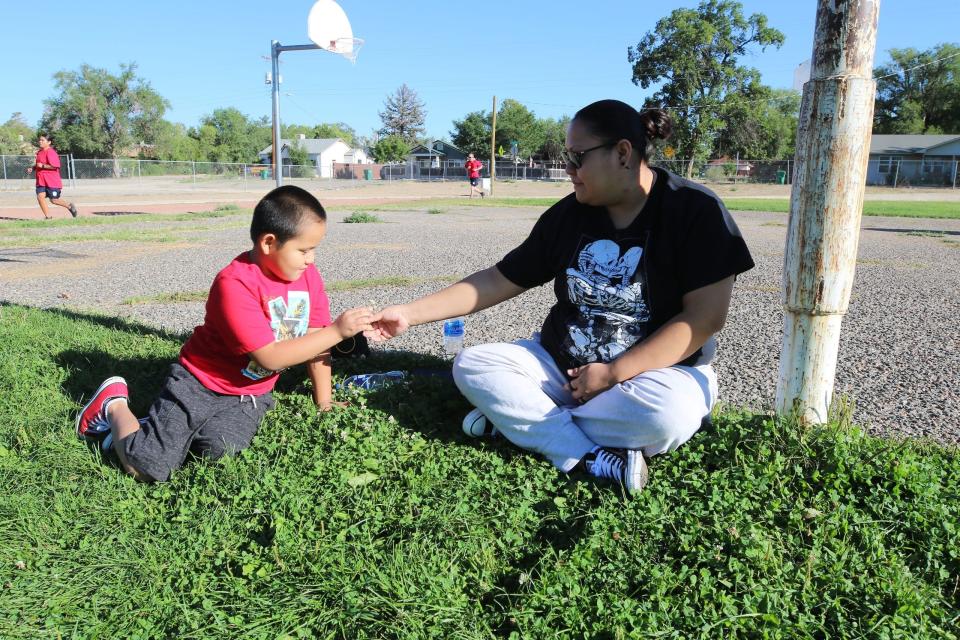 Jesse Lopez, left, and his mother Nikki Marks, sit on the grass on Aug. 24, 2021, on the old Tibbetts Middle School property in Farmington where city officials plan to build an all-abilities park.