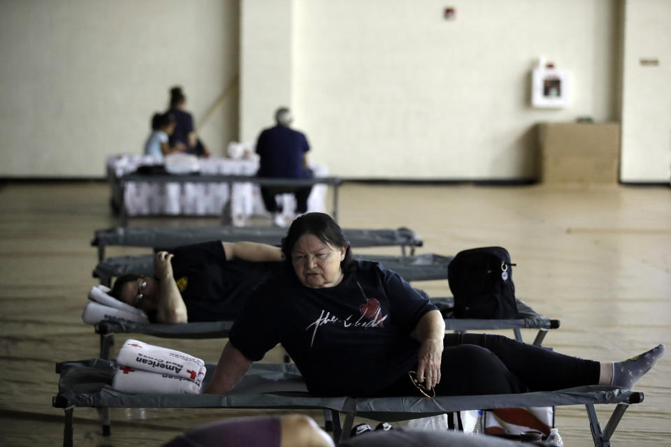 Mary Lewis, bottom, talks to a fellow evacuee from a brush fire dubbed Tick Fire at a shelter in the West Ranch High School gym Friday, Oct. 25, 2019, in Santa Clarita, Calif. (AP Photo/Marcio Jose Sanchez)