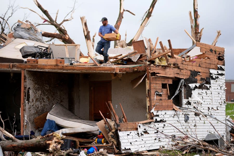 A man sorts through the remains of a home damaged by a tornado Tuesday, May 21, 2024, in Greenfield, Iowa. (AP Photo/Charlie Neibergall)