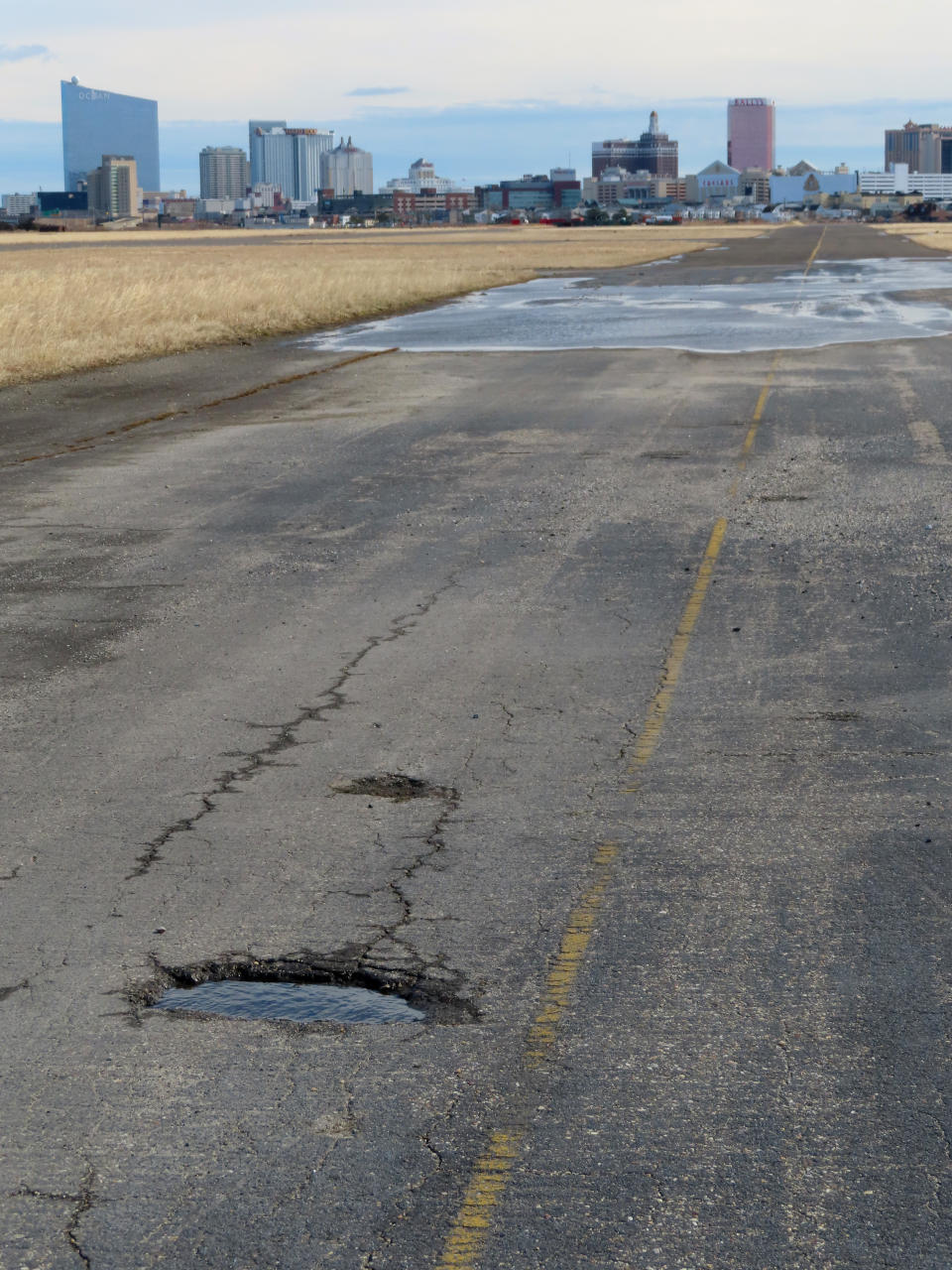 FILE: A pot-holed runway at the former Bader Field airport site is backdropped by casinos on Feb. 18, 2022, in Atlantic City, N.J. Two Philadelphia developers want to build a $3 billion housing, office and retail project on the site of the historic former airport in Atlantic City, the latest proposal for one of the largest tracts of buildable land near the ocean on the U.S. East Coast. (AP Photo/Wayne Parry, File)