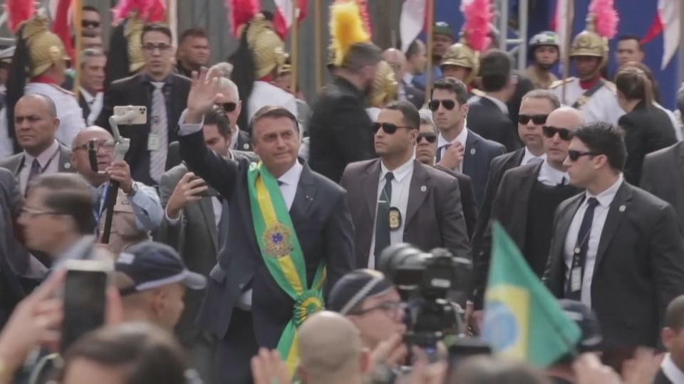 巴西總統波索納洛（揮手者），日前在巴西慶祝儀式的閱兵大典上拉票，公器私用招來批評。（路透社）