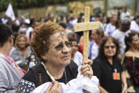 A woman holds a cross during a tribute to those who died in the dam disaster last year in Brumadinho city, Minas Gerais state, Brazil, Saturday, Jan.25, 2020. The wave of mud and debris that on Jan. 25, 2019 buried the equivalent of 300 soccer pitches and killed 270 people, continues to barrel over residents' minds, the local economy and the environment, one year later. (AP Photo/Gustavo Andrade)