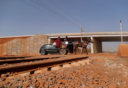 People ride a horse-drawn cart across the new railway tracks for a high speed rail in Mbao, on the outskirts of Dakar, Senegal February 12, 2019. Picture taken February 12, 2019. REUTERS/Zohra Bensemra