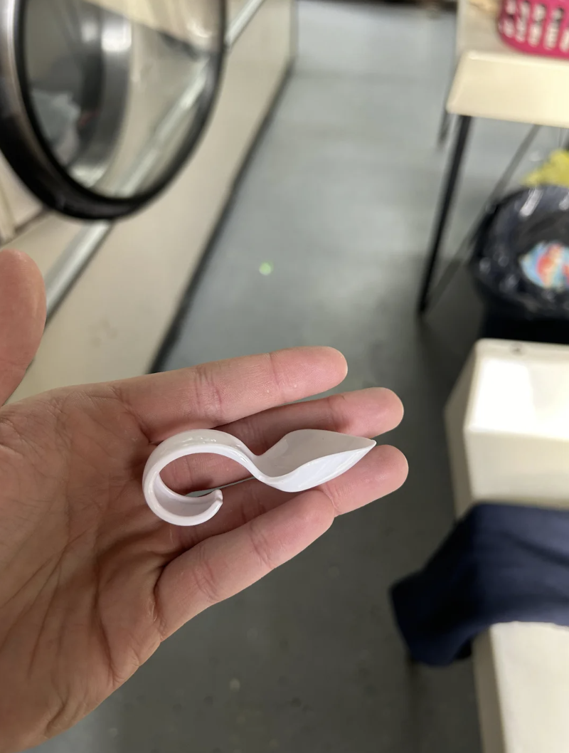 Person holding a twisted white plastic object, possibly a laundry detergent pod, in their hand