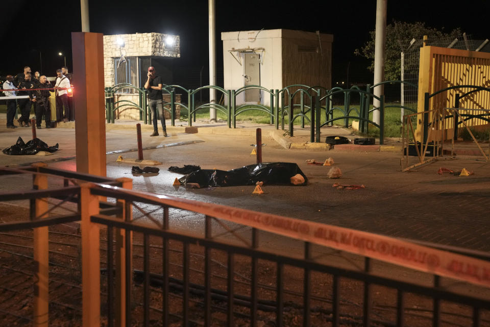 Israeli police officers stand next to the body of Palestinian attacker at the scene of a shooting attack outside the Israeli settlement of Maale Adumim, in the West Bank, Wednesday, Oct. 19, 2022. A Palestinian gunman who killed an Israeli soldier earlier this month was killed Wednesday after opening fire at a security guard at a West Bank settlement near Jerusalem. Israel Prime Minister Yair Lapid said Wednesday that Uday Tamimi, a Palestinian man from the Shuafat refugee camp near Jerusalem who was the subject of a more than weeklong manhunt by security forces, was killed by Israeli security forces. Police said he opened fire at a security guard, wounding him lightly. (AP Photo/Mahmoud Illean)