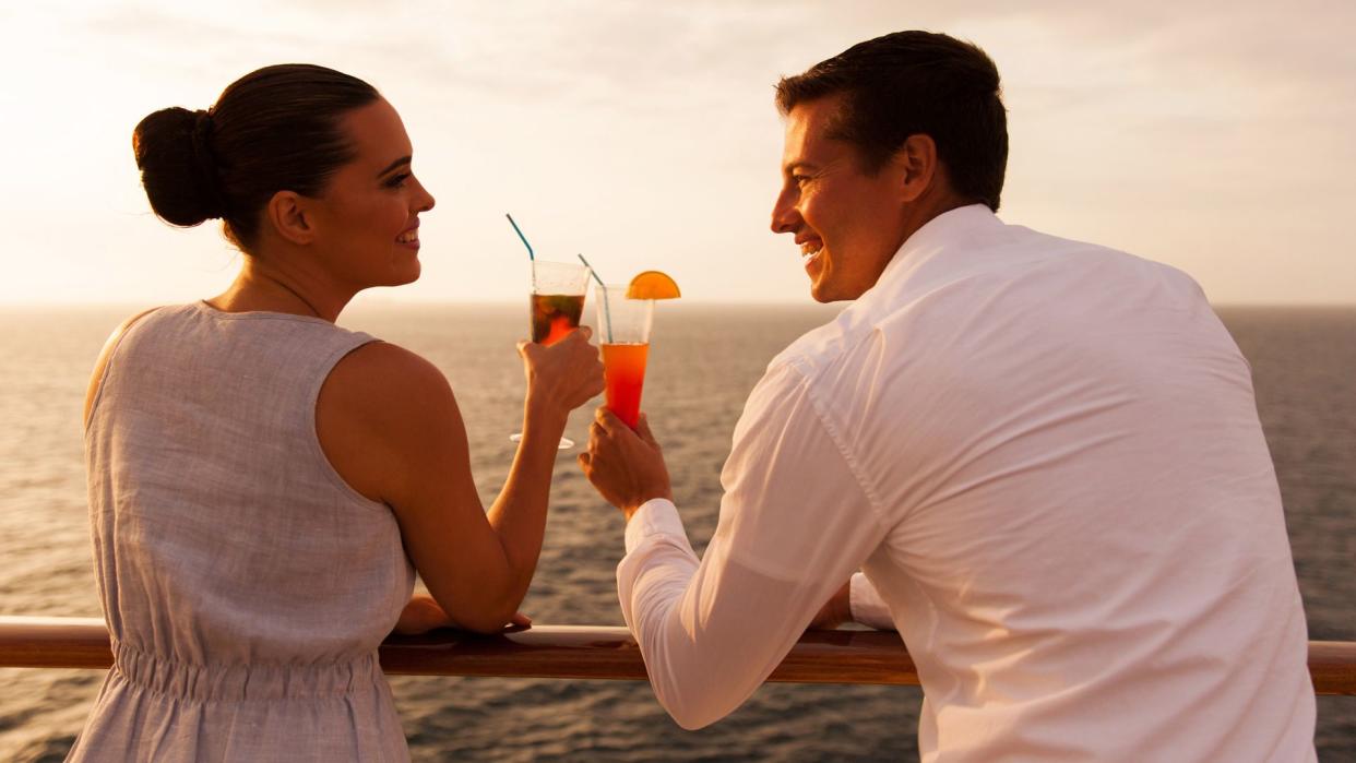 romantic young couple toasting with cocktail on cruise ship.