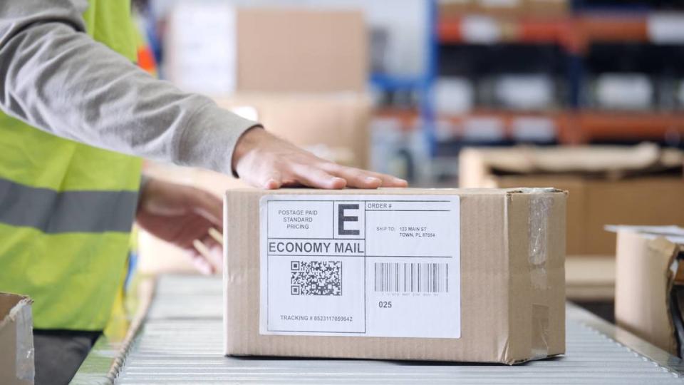 Distribution warehouse employee places a hand on a package ready for distribution.