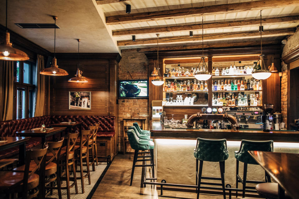 Classic bar interior with wooden accents, leather seating, and shelves stocked with bottles