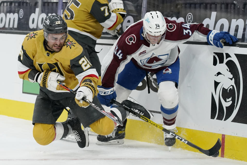 Vegas Golden Knights' William Carrier (28) vies for the puck with Colorado Avalanche's Jacob MacDonald during the second period of an NHL hockey game Sunday, Feb. 14, 2021, in Las Vegas. (AP Photo/John Locher)