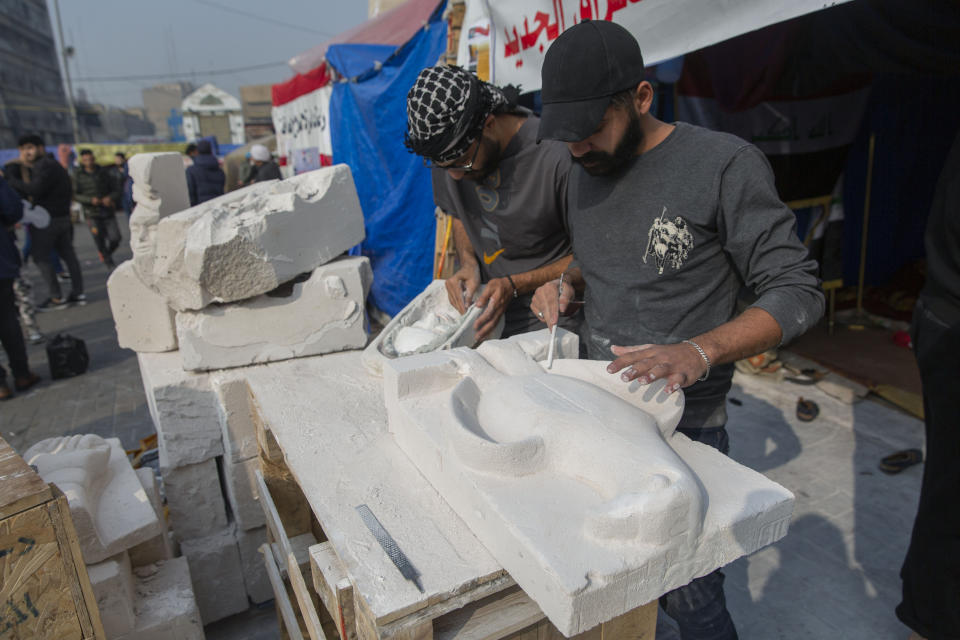 In this Sunday, Dec. 15, 2019, photo, young Iraqi trainees work on sculptures in preparation for their upcoming art exhibition, during the ongoing protests in Tahrir square, Baghdad, Iraq. Tahrir Square has emerged as a focus of the protests, with protesters camped out in dozens of tents. Dozens of people took part in the simple opening of the sculpture exhibition. (AP Photo/Nasser Nasser)