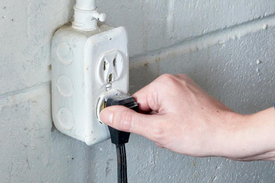 Woman unplugs her clothes dryer from the electrical outlet.