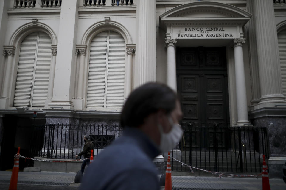 Hombres caminan frente al Banco Central en el distrito financiero de Buenos Aires durante una cuarentena ordenada por el gobierno para frenar la propagación de COVID-19 en Buenos Aires, Argentina, el jueves 21 de mayo de 2020. Argentina se encamina a un cese de pagos, el noveno de su historia, ante el probable incumplimiento de vencimientos de títulos por 503 millones de dólares. El impago se produciría en el marco de la extensión hasta el 2 de junio del plazo que el gobierno les dio a los acreedores para aceptar una oferta de reestructuración de la deuda por más de 66.000 millones dólares. (AP Foto / Natacha Pisarenko)