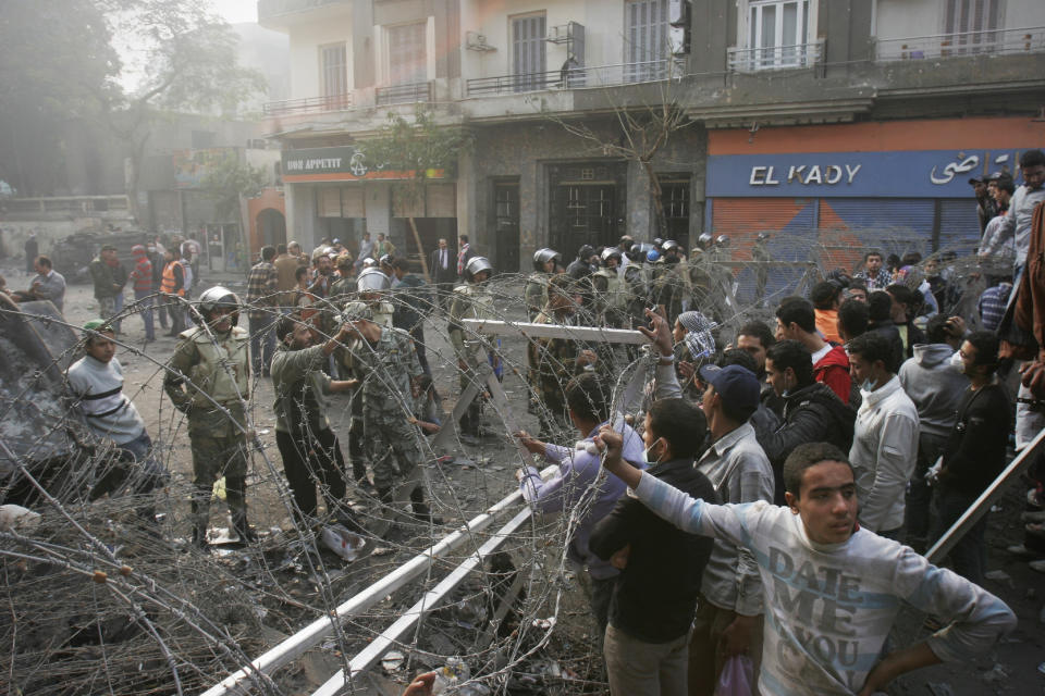 File - In this Thursday, Nov. 24, 2011 file photo, Egyptian protesters stand behind a barbed wire barricade in Tahrir Square in Cairo, Egypt. Ten years ago, an uprising in Tunisia opened the way for a wave of popular revolts against authoritarian rulers across the Middle East known as the Arab Spring. For a brief window as leaders fell, it seemed the move toward greater democracy was irreversible. Instead, the region saw its most destructive decade of the modern era. Syria, Yemen, Libya and Iraq have been torn apart by wars, displacement and humanitarian crisis. (AP Photo/Mohammed Abu Zaid)