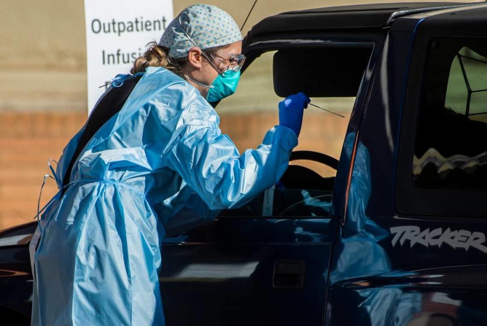 A healthcare worker administers a COVID-19 test in the parking lot of Mercy General Hospital in Sacramento on Tuesday, Dec. 1, 2020.