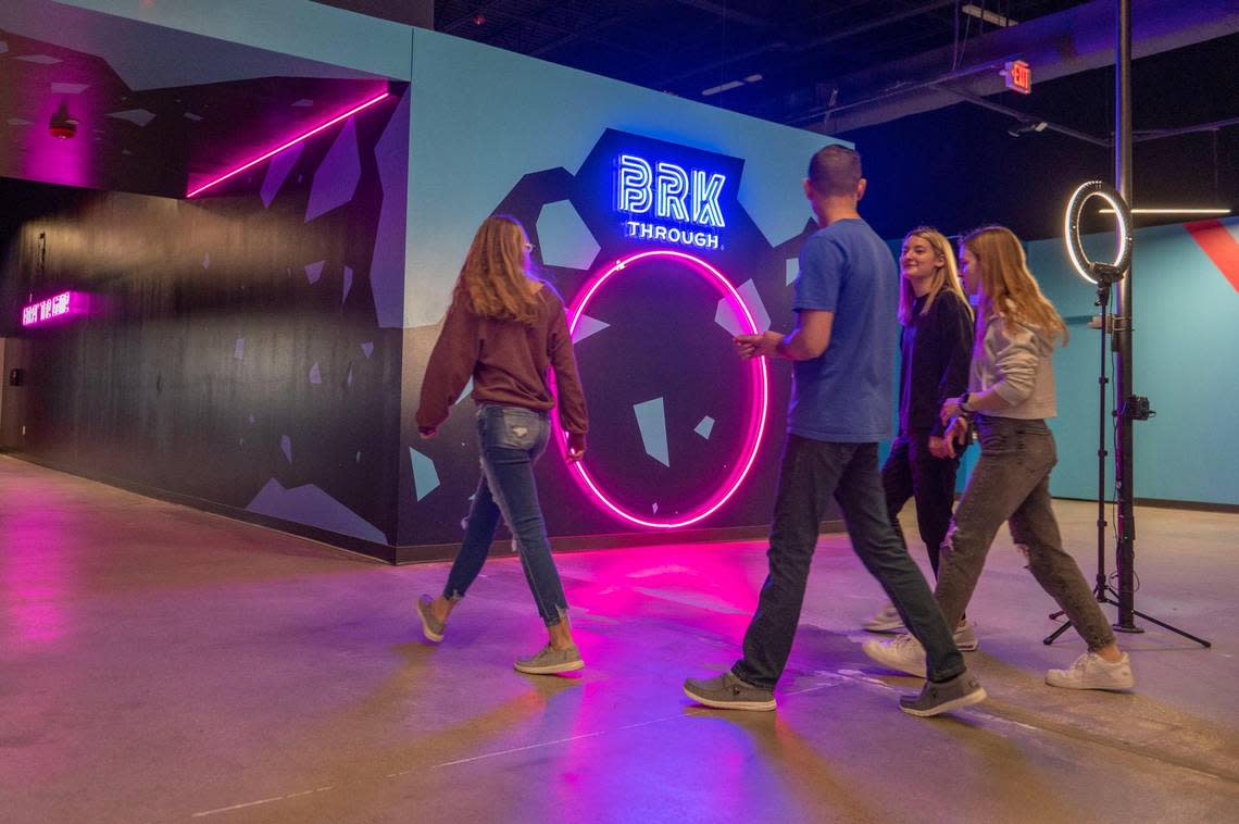 Visitors walk to the photo booth area at Brkthrough recreation center. The space has nearly 40 interactive game rooms, a restaurant and a self-pour tap wall.