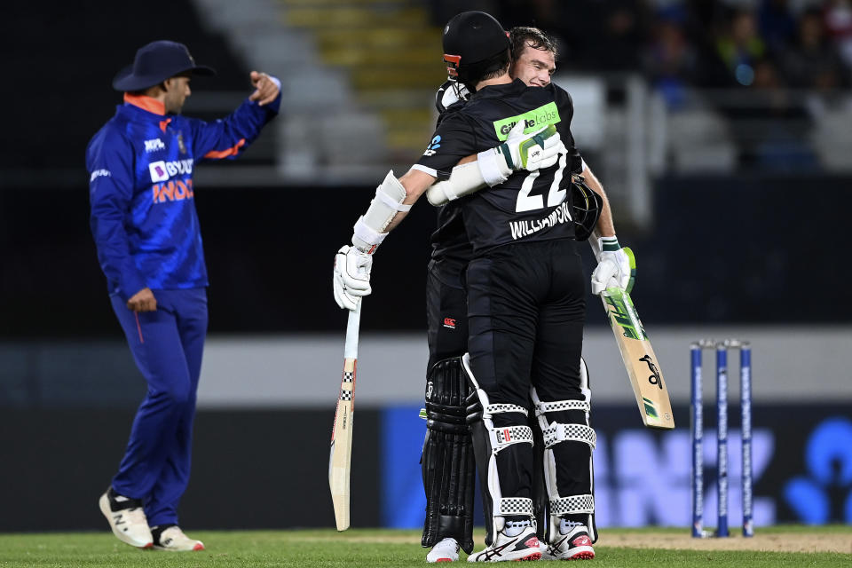 New Zealand's Tom Latham, center, celebrates his century with batting partner Kane Williamson while playing India in their one day international cricket match in Auckland, New Zealand, Friday, Nov. 25, 2022. (Andrew Cornaga/Photosport via AP)