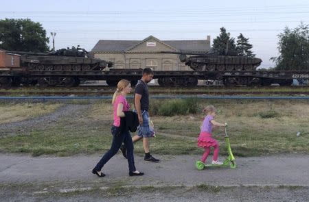 Tanks are seen on a freight train shortly after its arrival at a railway station, with people walking in the foreground, in the Russian southern town of Matveev Kurgan, near the Russian-Ukrainian border in Rostov region, Russia, May 26, 2015. REUTERS/Maria Tsvetkova