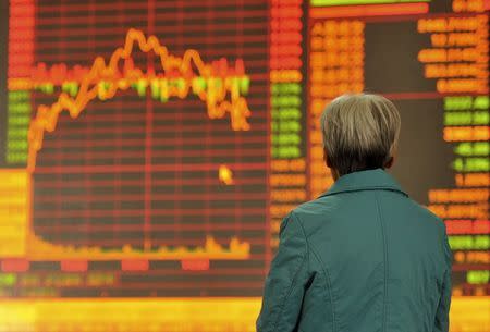 An investor stands in front of an electronic board showing stock information at a brokerage house in Fuyang, Anhui province, China, November 2, 2015. REUTERS/Stringer