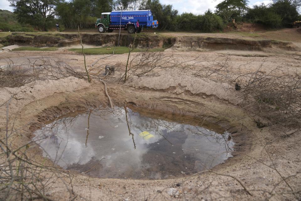 A vendor fills a tanker with water to be sold to residents from a hole in the sandy riverbed in Makueni County, Kenya Thursday, Feb. 29, 2024. (AP Photo/Brian Inganga)