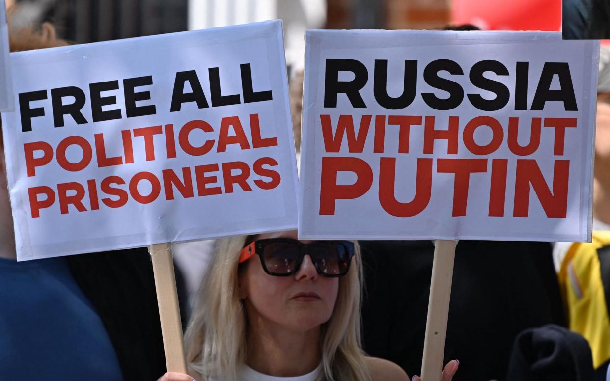 A protester holds up placards at a gathering outside the Russian Embassy in London - AFP