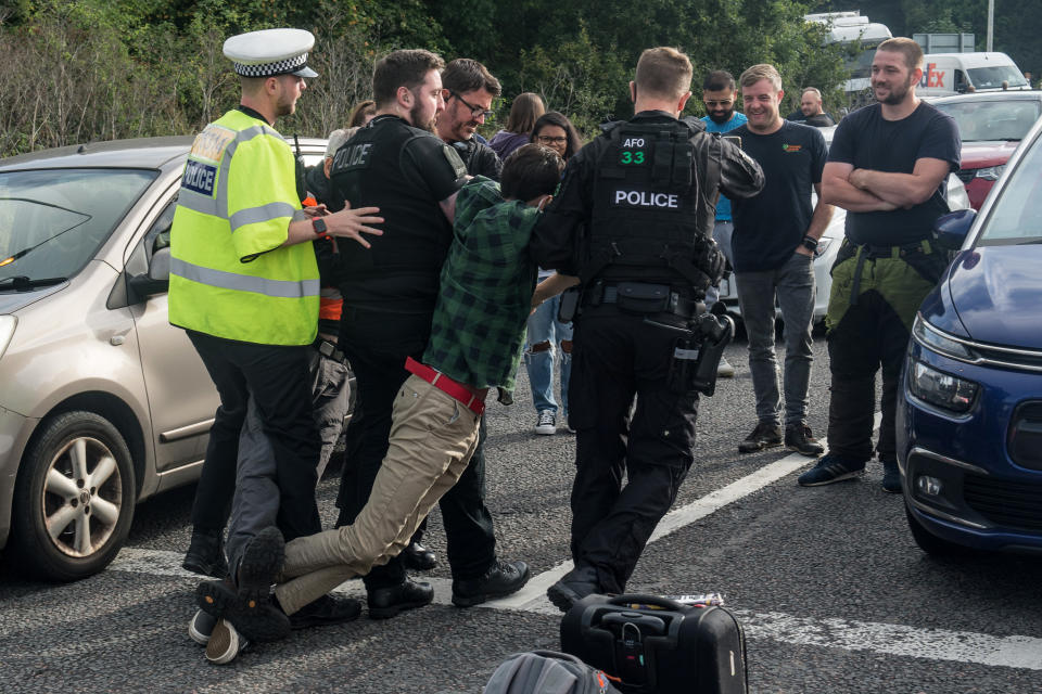 ESSEX, ENGLAND - SEPTEMBER 17: Police arrest activists as protesters from the Insulate Britain pressure group block a roundabout near Stansted Airport on September 17, 2021 in Stansted, Essex. (Photo by Guy Smallman/Getty Images)