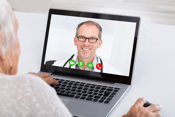 A doctor video conferencing in with an elderly patient using her computer.