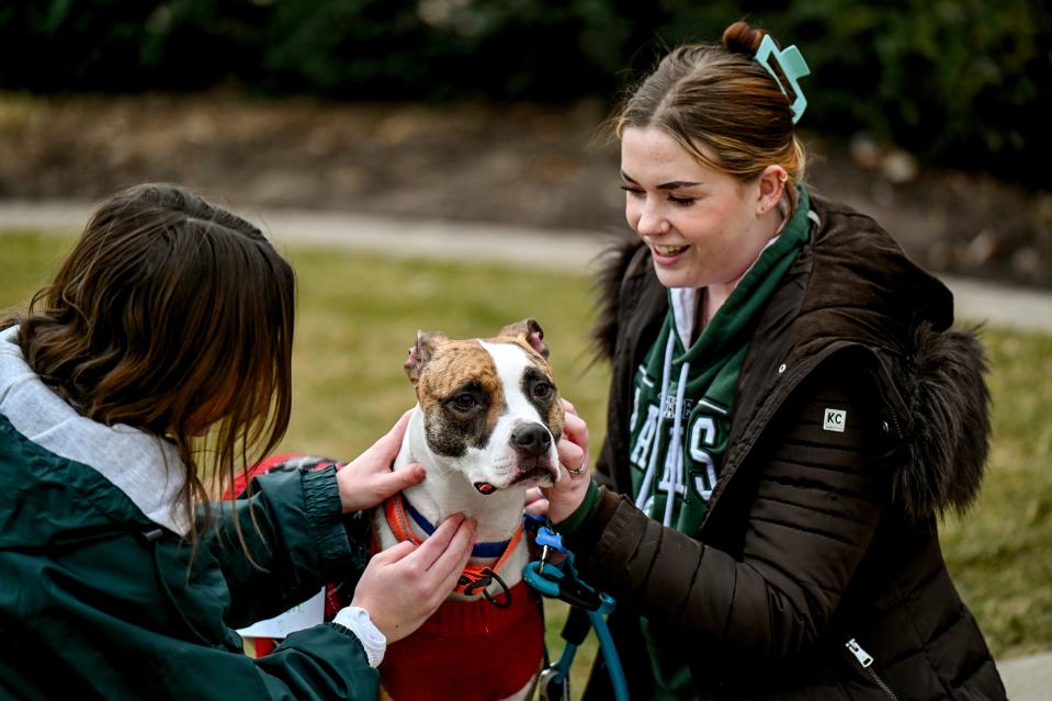 Michigan State University senior Allie Hukill, right, offers her dog Benny, center, for 'free puppy kisses' to those at the Sparty statue one year after the mass shooting at MSU on Tuesday, Feb. 13, 2024, in East Lansing.