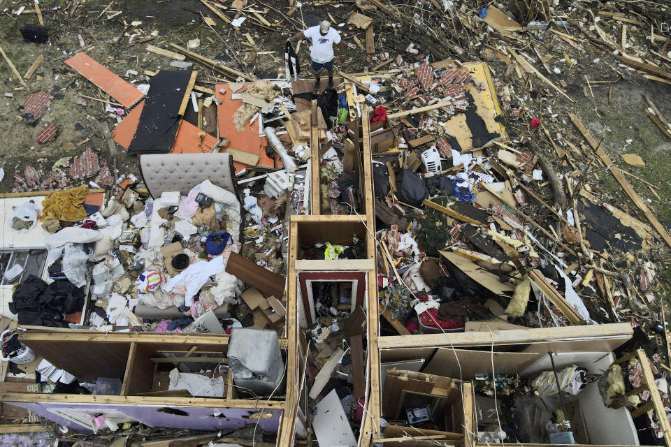 FILE - A man, top center, salvages a jacket as he looks over a tornado damaged home, March 26, 2023, in Rolling Fork, Miss. An unusual weather pattern has set in, triggering the devastating tornado that hit Rolling Fork, and meteorologists fear this Friday, March 31, will be one of the worst days, with much more to come. (AP Photo/Julio Cortez, File)