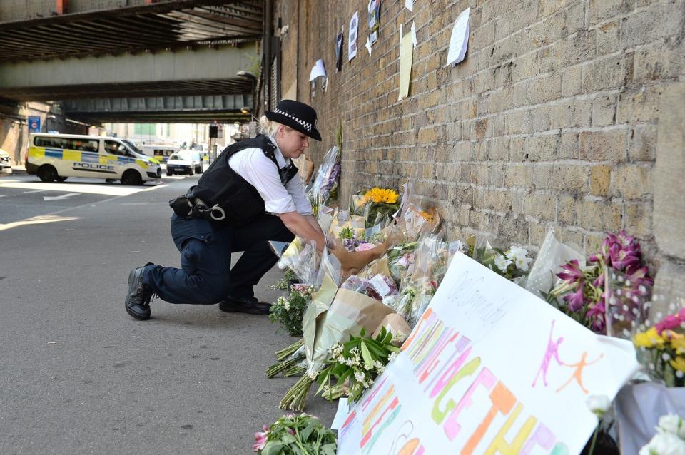 A police officer laying some flowers passed over by a member of the public (PA)