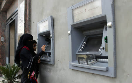 A Palestinian woman checks her balance via an automated teller machine (ATM) outside a bank in Gaza City April 12, 2018. REUTERS/Ibraheem Abu Mustafa