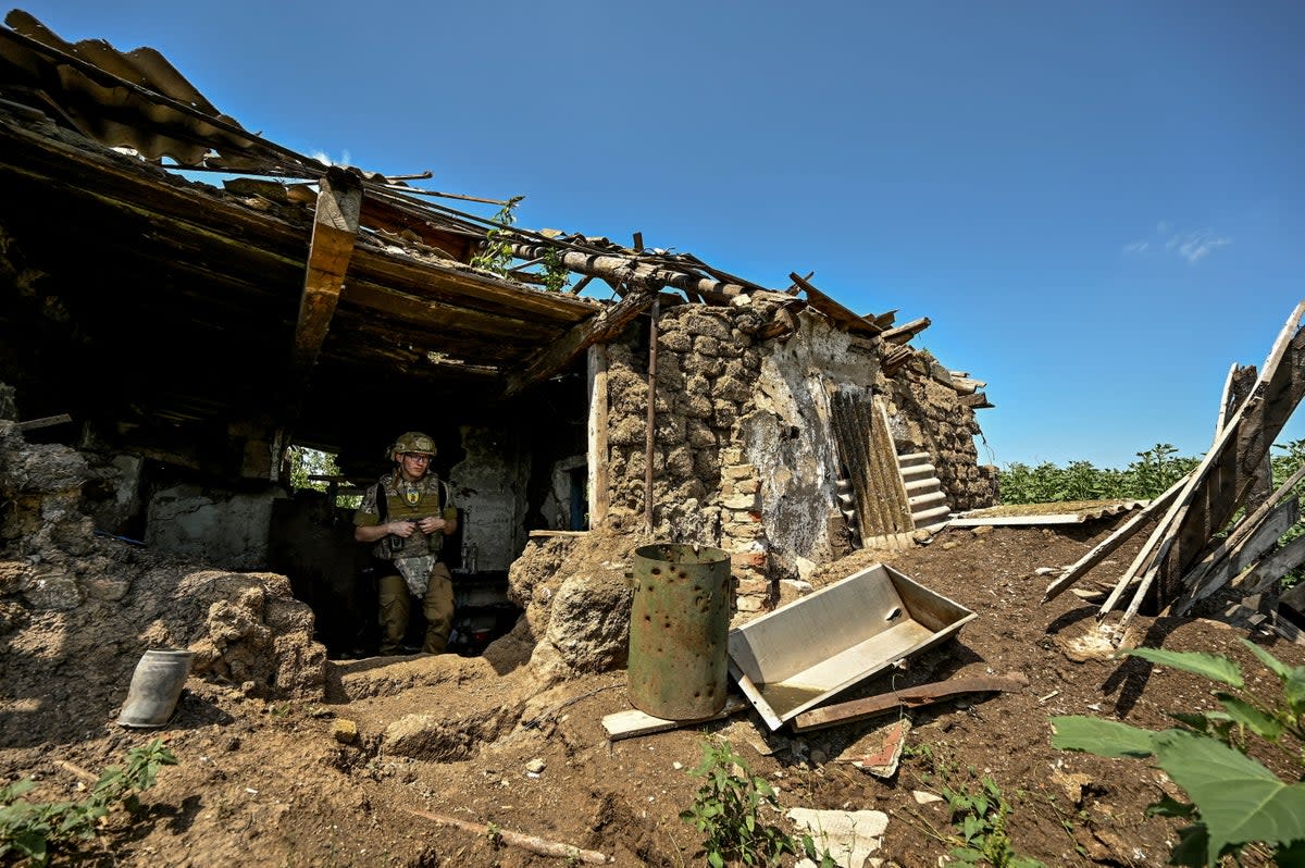 Ukrainian serviceman inspects a former position of Russian troops in the recently liberated village of Novodarivka (Reuters)