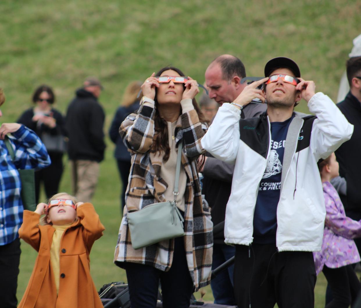From left to right: Maeve Chichester, Bridget Chichester and Tim Chichester take in the partial solar eclipse at Shawmut Park in Hornell Monday, April 8, 2024.