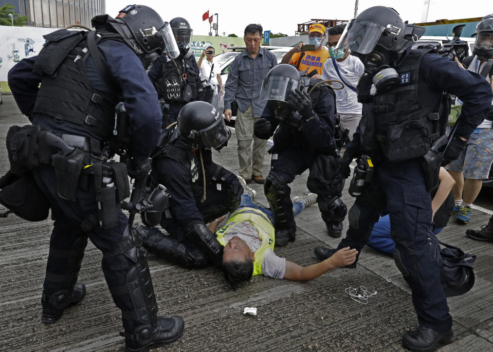 FILE - In this file photo taken Wednesday, June 12, 2019, a cameraman lies injured after riot police fire tear gas on protesters outside the Legislative Council in Hong Kong. Hong Kong police have resorted to harsher-than-usual tactics to suppress protesters this week in the city’s most violent turmoil in decades. Police fired rubber bullets and beanbag rounds at the crowds, weapons that have not been widely used in recent history. (AP Photo/Vincent Yu, File)