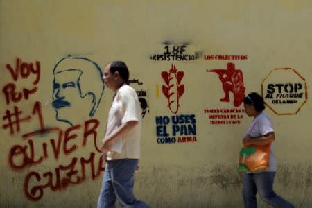 People walk past pro-government graffiti in Caracas, Venezuela, August 7, 2017. REUTERS/Ueslei Marcelino