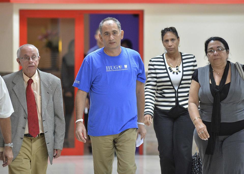 Felix Baez (2nd L), a member of the International Contingent Brigade "Henry Reeve", who was infected with Ebola in Sierra Leone, arrives at the Jose Marti International Airport in Havana December 6, 2014. A Cuban doctor who contracted Ebola while treating patients in Sierra Leone returned home to Cuba on Saturday, cured after 16 days in a Geneva hospital where he received an experimental treatment. Baez, 43, was one of 256 Cuban doctors and nurses who went to West Africa to treat patients from the worst outbreak of the virus on record, which has killed more than 6,000 people. Baez was met at Havana's Jose Marti airport by his wife, elder son and Health Minister Roberto Morales, among others, officials said. REUTERS/Yamil Lage/Pool (CUBA - Tags: HEALTH)