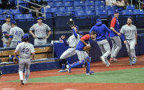 Texas Rangers left fielder Eli White, center, chases down a foul ball in the Texas bullpen hit by Tampa Bay Rays' Joey Wendle during the fourth inning of a baseball game Thursday, April 15, 2021, in St. Petersburg, Fla. (AP Photo/Steve Nesius)