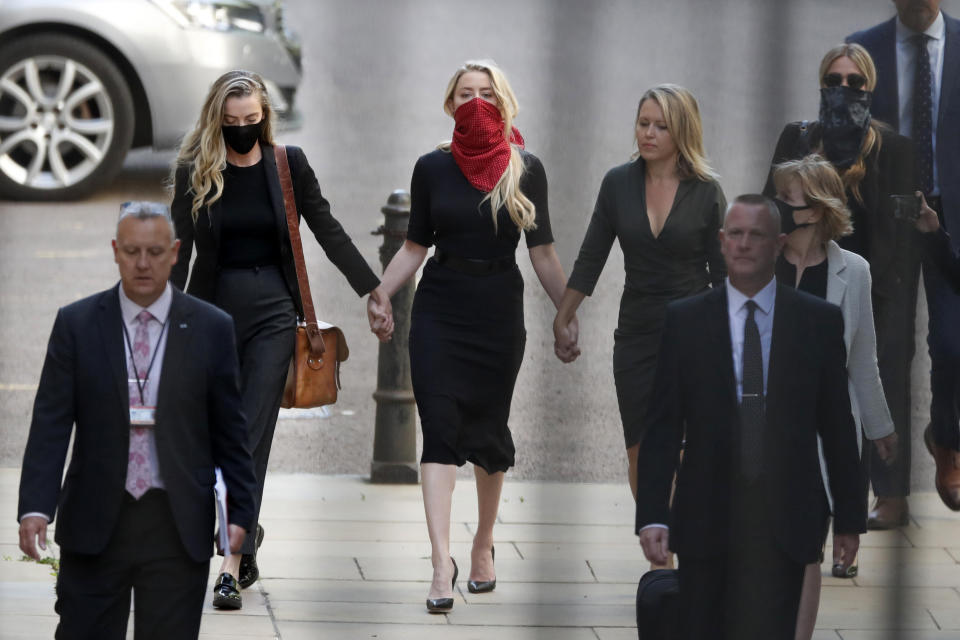 Amber Heard, center, arrives at the High Court in London, Tuesday, July 7, 2020. Johnny Depp has a starring role in a real-life courtroom drama in London, where he is suing a tabloid newspaper for libel over an article that branded him a "wife beater." On Tuesday, a judge at the High Court is due to begin hearing Depp's claim against The Sun's publisher, News Group Newspapers, and its executive editor, Dan Wootton, over the 2018 story alleging he was violent and abusive to then-wife Amber Heard. Depp strongly denies the claim. (AP Photo/Alastair Grant)