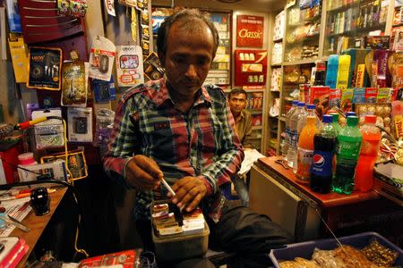 A shopkeeper takes out a cigarette from a box for a customer in Kolkata October 15, 2014. REUTERS/Rupak De Chowdhuri