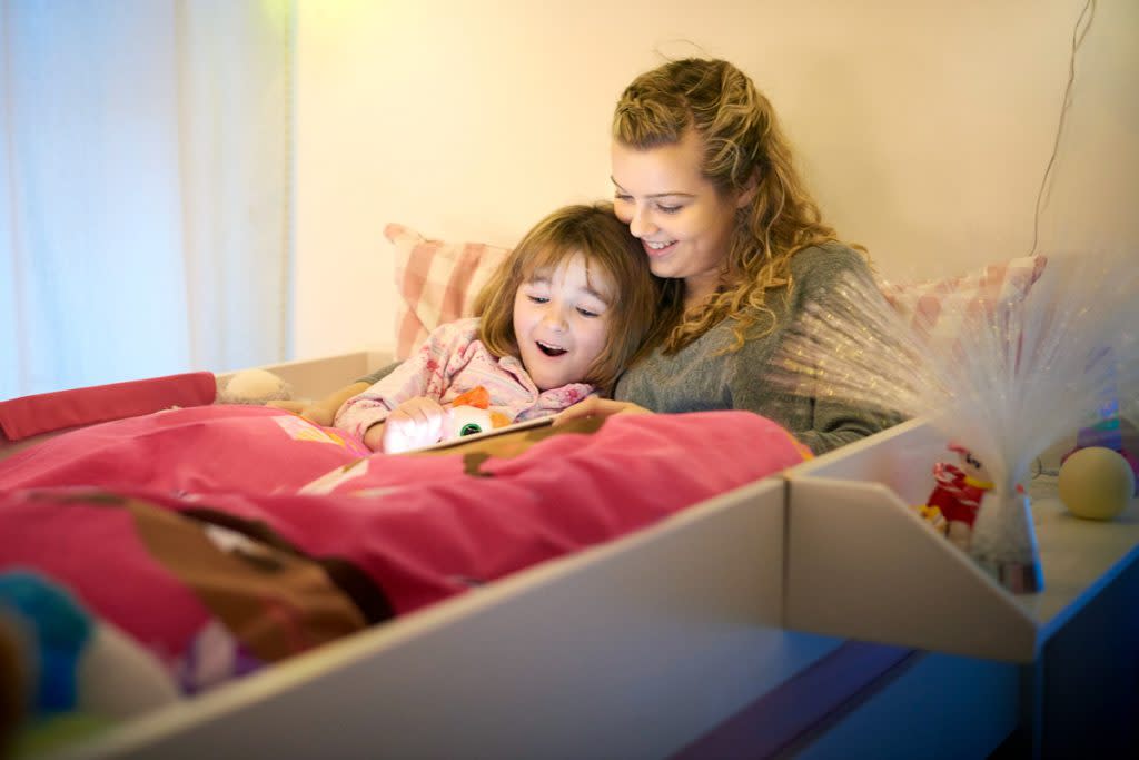 A nanny reads a bedtime story to a child. 