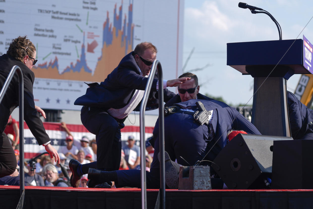 Trump is covered by Secret Service agents onstage after gunfire at his campaign rally. 