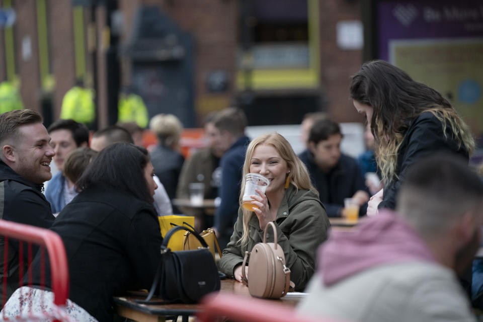 Members of the public are seen at a bar in Manchester's Northern Quarter, England, Saturday July 4, 2020. England is embarking on perhaps its biggest lockdown easing yet as pubs and restaurants have the right to reopen for the first time in more than three months. In addition to the reopening of much of the hospitality sector, couples can tie the knot once again, while many of those who have had enough of their lockdown hair can finally get a trim. (AP Photo/Jon Super)