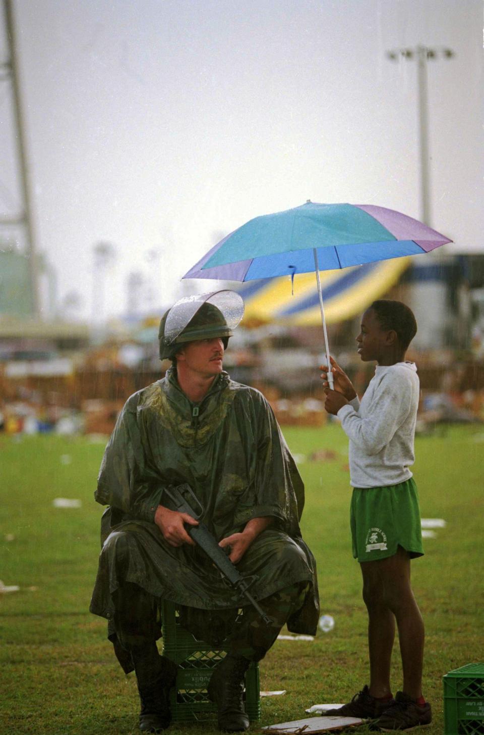 <p>Jerome Mitchell, 10, holds an umbrella as he chats with National Guardsman Toddy Bryan of Palmetto, Fla., at a food and clothing distribution center in Florida City, Fla., Aug. 30, 1992. Food and clothing are being given to victims of Hurricane Andrew. (AP Photo/Lynne Sladky) </p>