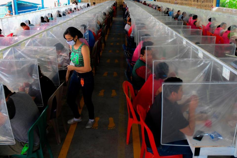 Workers at the factory have lunch separated by plastic panels as a preventive measure against the spread of Covid-19.