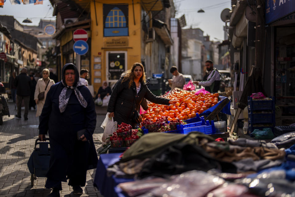 People buy food and goods in a street market in Istanbul, Turkey, Tuesday, Feb. 27, 2024. Turkey was coming to terms on Monday with the opposition's unexpected success in local elections which saw it outperform President Recep Tayyip Erdogan's ruling party and add to municipalities gained five years ago. (AP Photo/Francisco Seco)