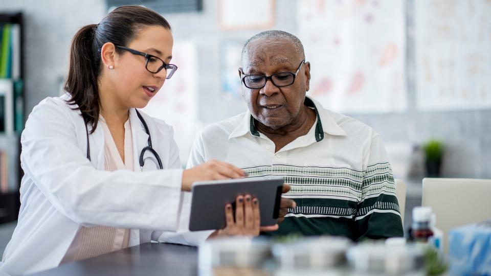 A senior man of African descent is indoors in a hospital room.