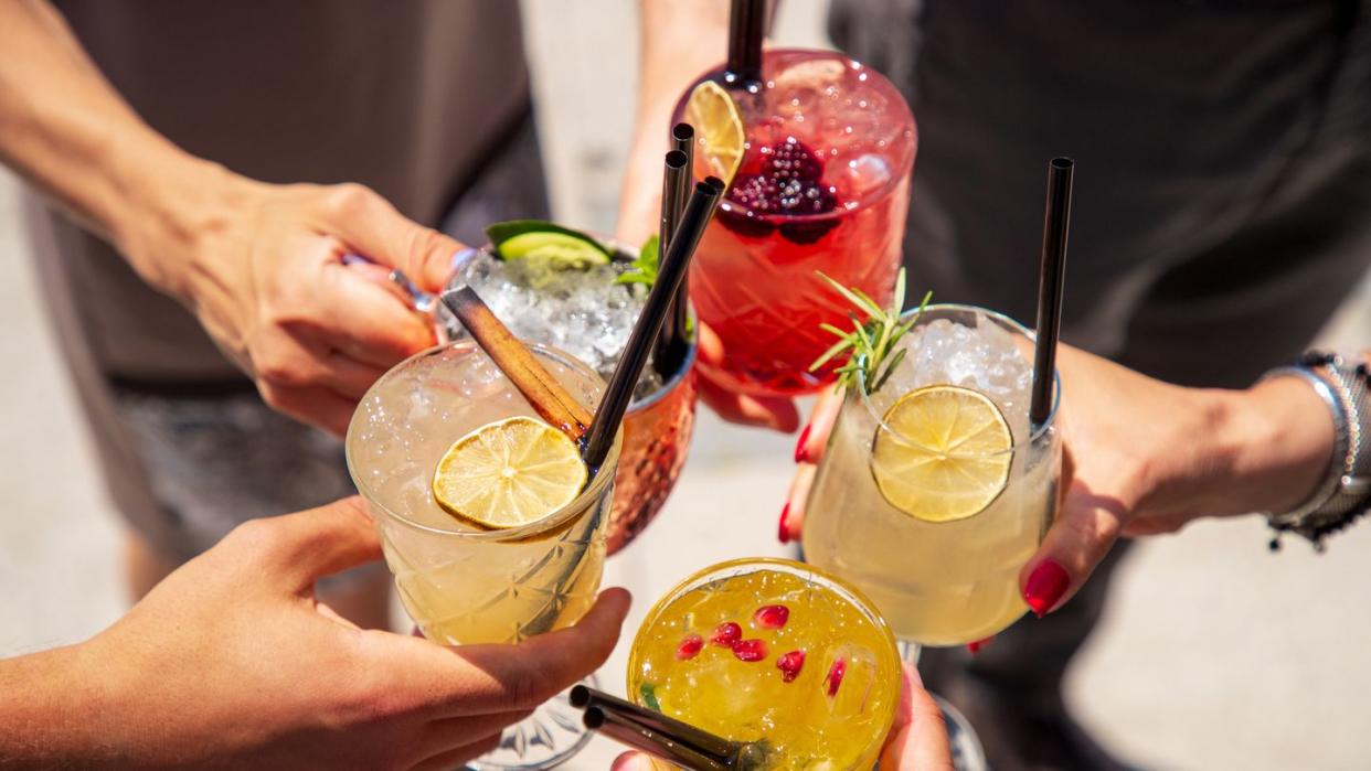 five cocktails in hands joined in celebratory toast