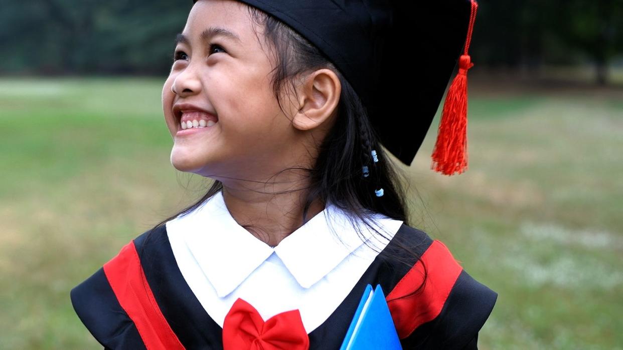 young child smiling in graduation cap and gown