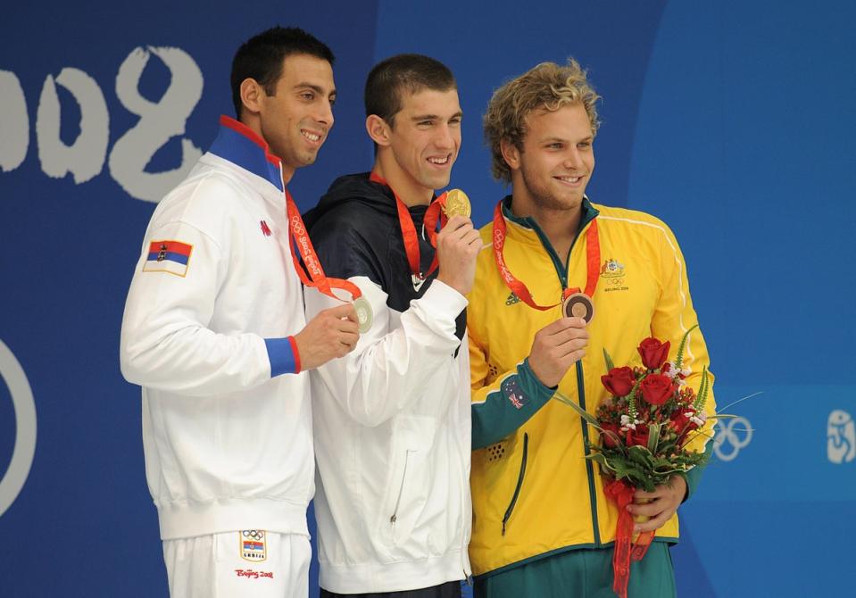 Michael Phelps, centre, with his men’s 100m butterfly final gold (Gareth Copley/PA) (PA Archive)