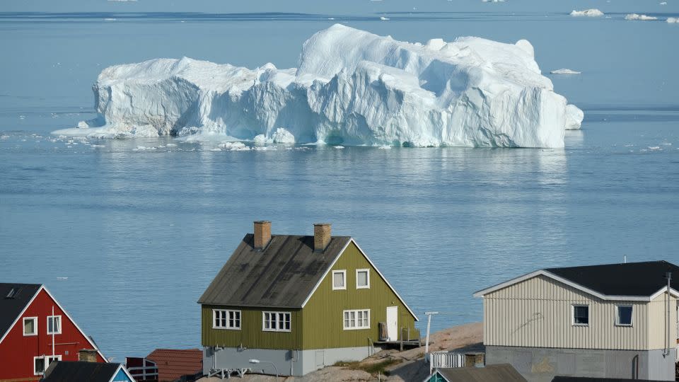 An iceberg floats past houses in Disko Bay, Greenland, during above-normally warm weather on July 30, 2019.  -Sean Gallup/Getty Images